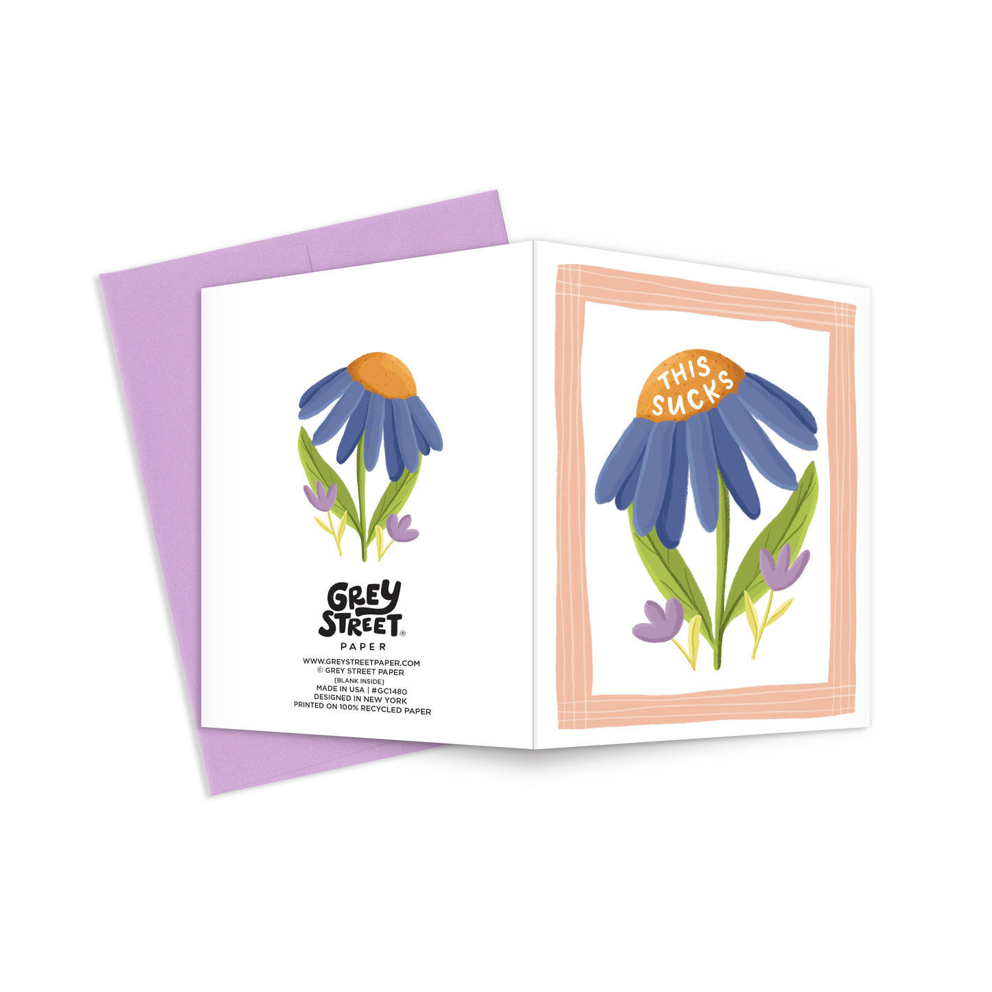 Full view of a greeting card with an illustration of a blue and purple flowers on the front reading this sucks and a blue flower on the back.