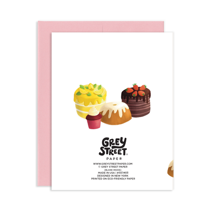 Back view of a greeting card with an illustration of lemon cake, German chocolate cake, and cupcake with a pink envelope.  