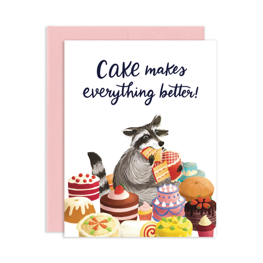 Greeting card with an illustration of a cute raccoon eating cake surrounded by assorted cakes and a pink envelope. Reads Cake Makes Everything Better in cursive letters.