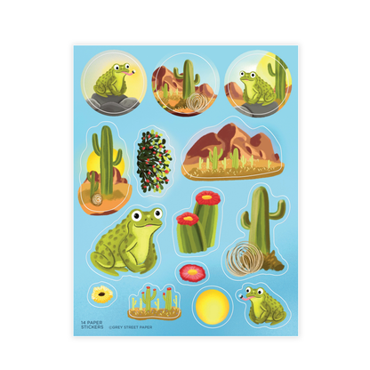 Desert toad and cactus sticker sheet with 14 paper stickers including green frogs, saguaro cacti, red mountains, tumbleweed, and red flowers on light blue background 