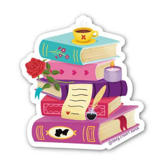 Stack of colorful books with a cup of tea, rose, and candle on a white background