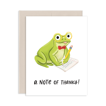 Greeting card with a cartoon frog with a red bow tie and yellow pencil writing  on a sheet of paper with 'a note of thanks!' on a white background