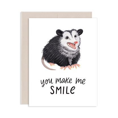 Card with an illustration of an opossum and text 'you make me smile' on a white background.